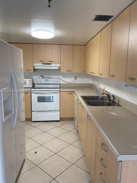 kitchen featuring light brown cabinets, white appliances, and sink