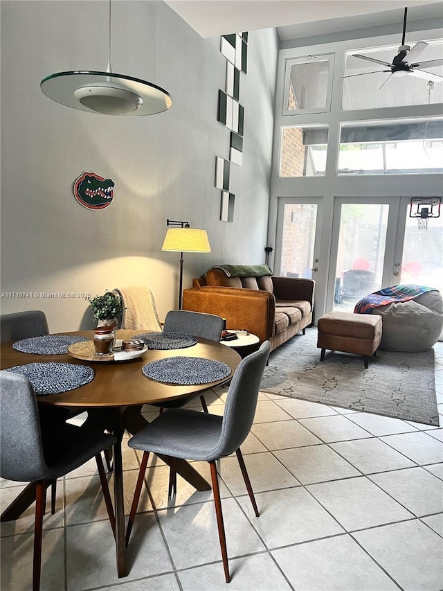 dining area with light tile patterned floors, a towering ceiling, french doors, and ceiling fan