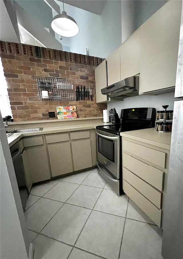 kitchen with cream cabinetry, light tile patterned floors, electric range, and a towering ceiling