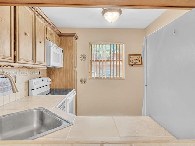 kitchen featuring white appliances, tile counters, light brown cabinetry, decorative backsplash, and sink