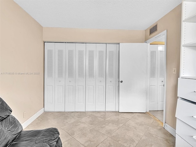 bedroom featuring light tile patterned flooring, a closet, and a textured ceiling