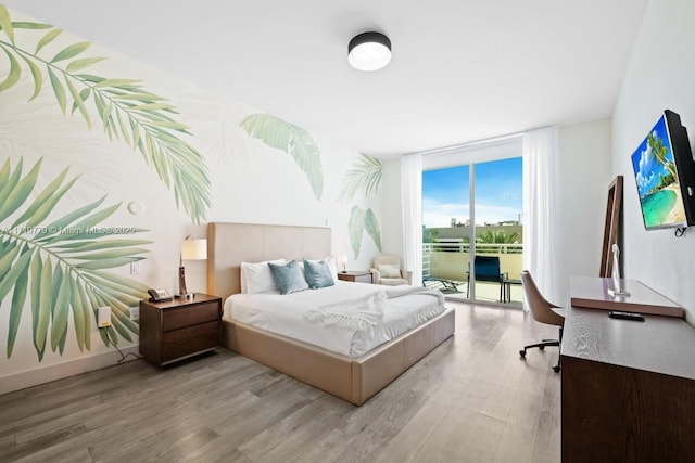 bedroom featuring expansive windows, access to outside, and light hardwood / wood-style flooring