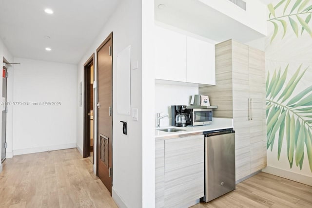 kitchen featuring light hardwood / wood-style floors, sink, white cabinets, and fridge