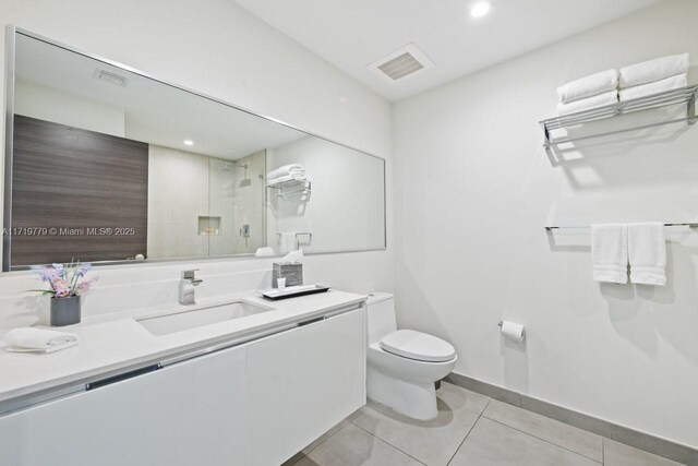 bathroom with toilet, vanity, tile patterned flooring, and walk in shower