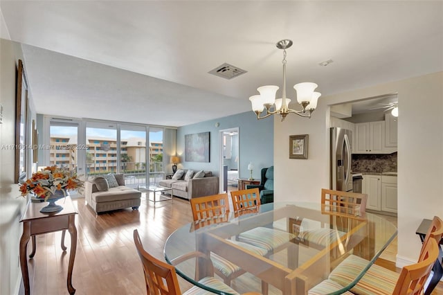 dining area featuring expansive windows, light hardwood / wood-style flooring, and a notable chandelier