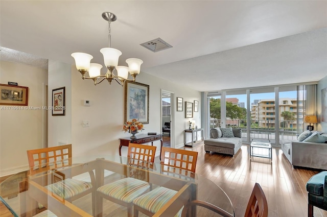 dining area featuring an inviting chandelier, a wall of windows, and light hardwood / wood-style floors