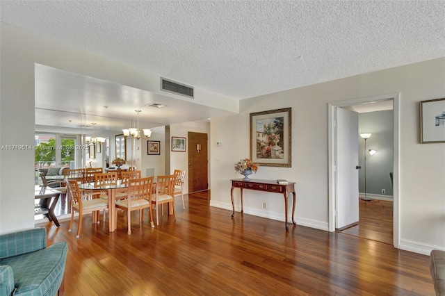 dining space with dark wood-type flooring, a chandelier, and a textured ceiling