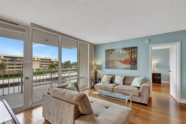 living room with light hardwood / wood-style flooring, expansive windows, and a textured ceiling