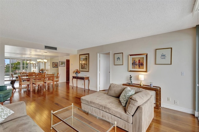 living room featuring an inviting chandelier, hardwood / wood-style floors, and a textured ceiling