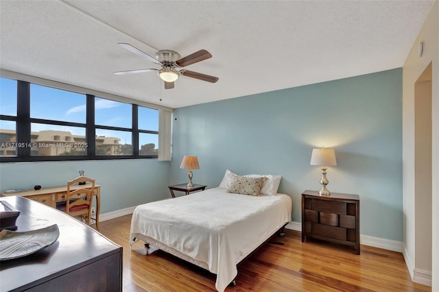 bedroom featuring ceiling fan, hardwood / wood-style floors, and a textured ceiling