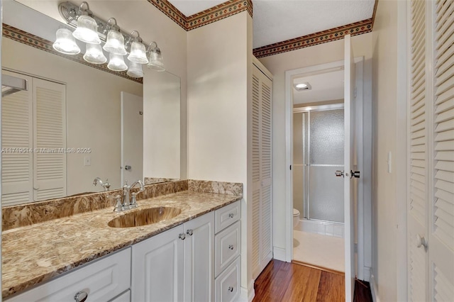 bathroom with vanity, toilet, hardwood / wood-style floors, and walk in shower