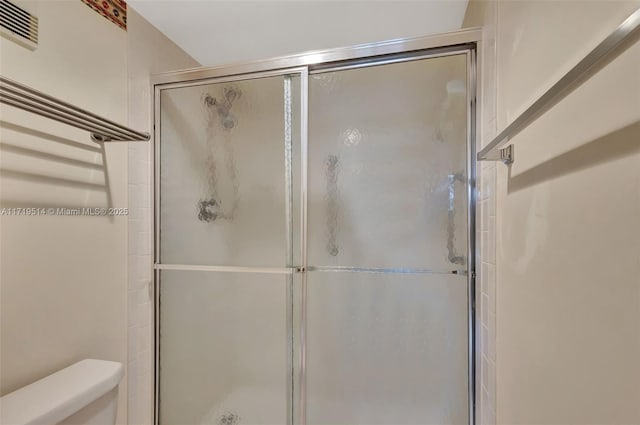 bathroom featuring toilet and a shower with door