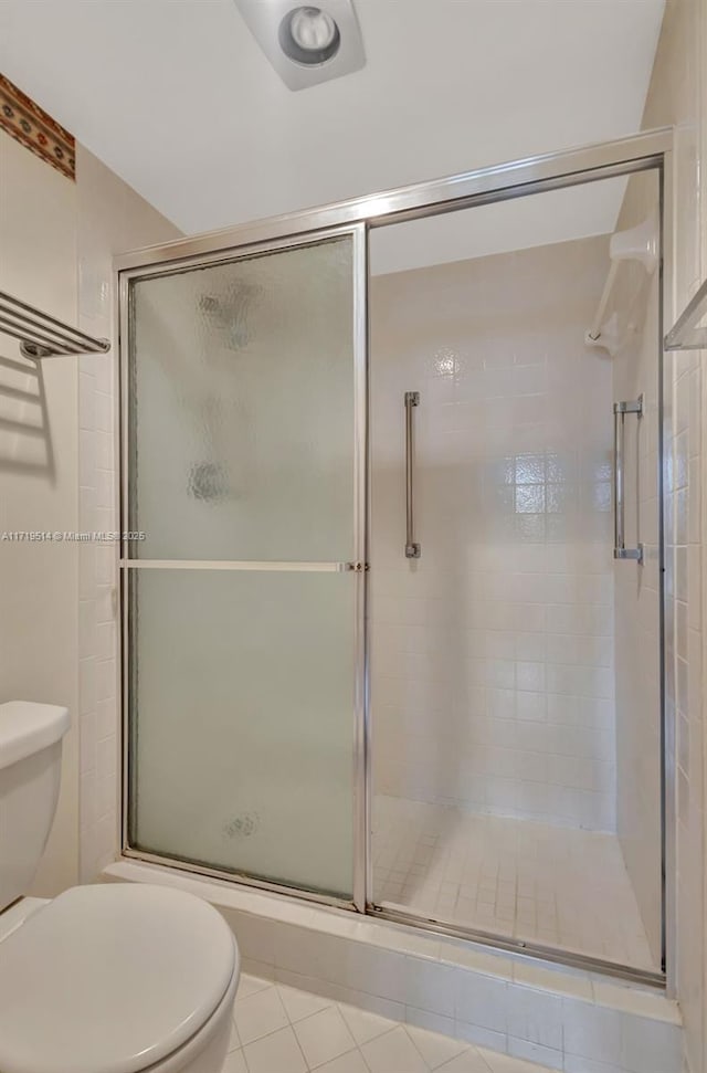 bathroom featuring tile patterned floors, toilet, and an enclosed shower