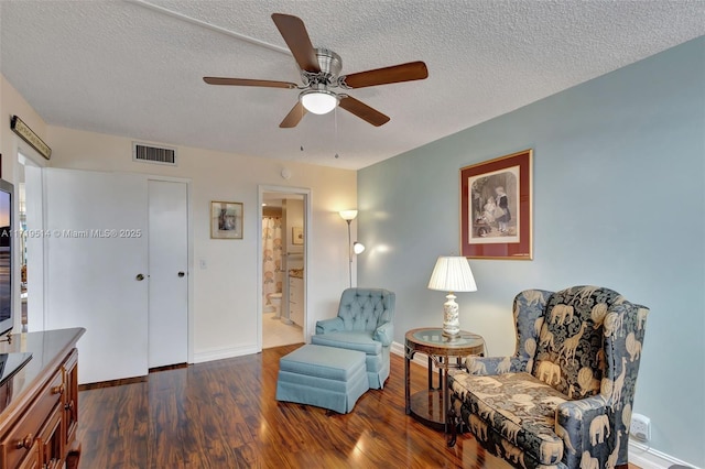 sitting room with dark hardwood / wood-style flooring, ceiling fan, and a textured ceiling