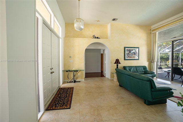 interior space featuring light tile patterned floors, a towering ceiling, and a notable chandelier