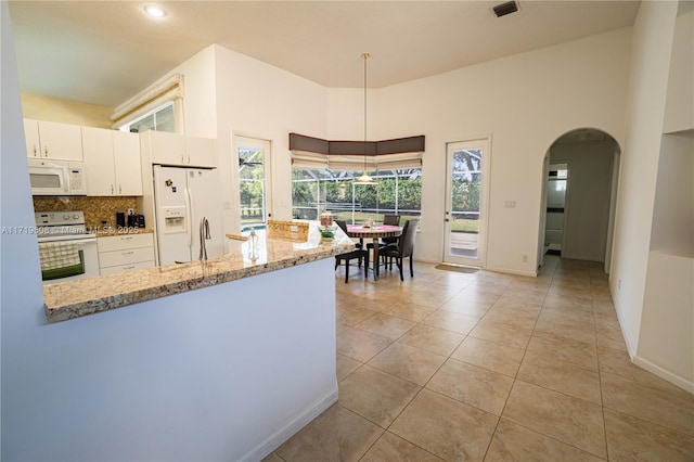 kitchen with light stone countertops, white cabinets, decorative light fixtures, and white appliances