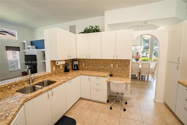 kitchen featuring kitchen peninsula, decorative backsplash, white cabinetry, and sink