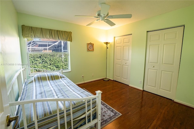 bedroom featuring ceiling fan, dark hardwood / wood-style floors, and two closets