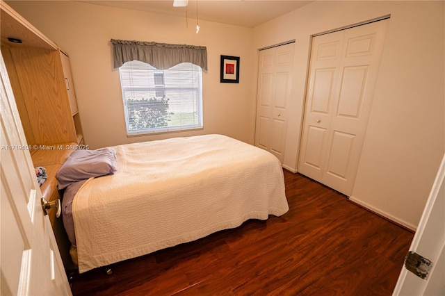 bedroom featuring multiple closets and dark wood-type flooring