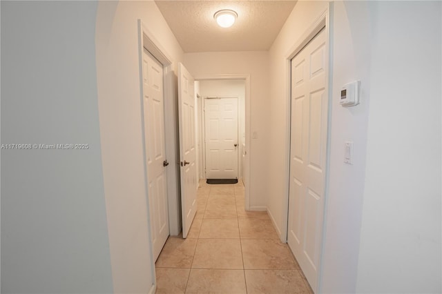 hall with light tile patterned floors and a textured ceiling