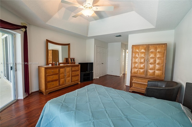 bedroom with a raised ceiling, ceiling fan, and dark wood-type flooring