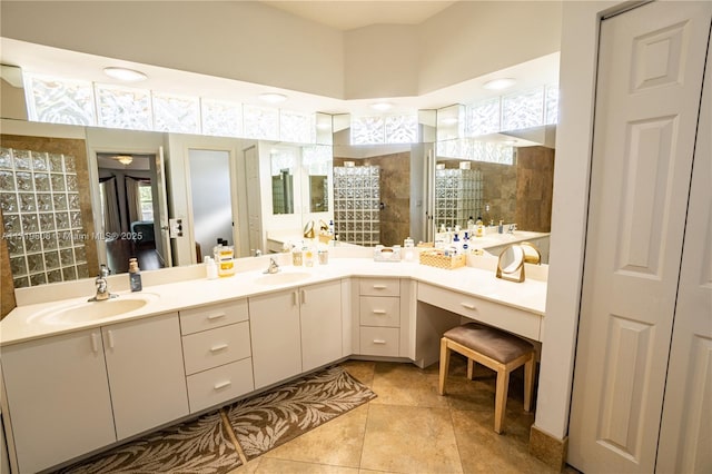 bathroom featuring tile patterned flooring, vanity, and a tile shower