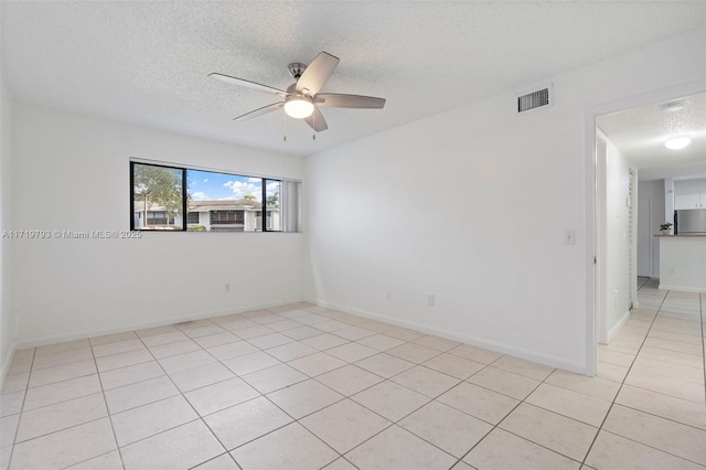 tiled spare room with a textured ceiling and ceiling fan