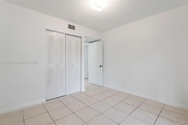 unfurnished bedroom with light tile patterned floors, a textured ceiling, and a closet