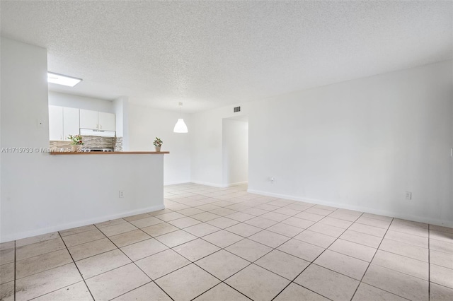 unfurnished room featuring light tile patterned flooring and a textured ceiling