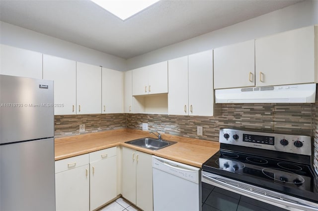 kitchen featuring sink, light tile patterned floors, decorative backsplash, white cabinets, and appliances with stainless steel finishes