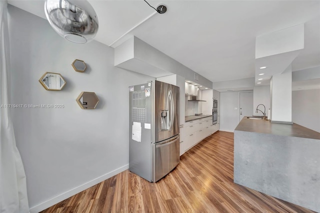 kitchen featuring light wood-type flooring, sink, stovetop, stainless steel fridge with ice dispenser, and white cabinetry