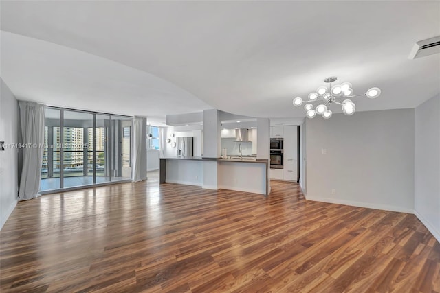 unfurnished living room featuring dark hardwood / wood-style flooring, a wall of windows, sink, and an inviting chandelier