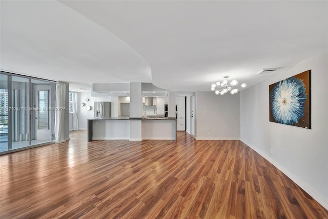 unfurnished living room with a notable chandelier, wood-type flooring, and sink