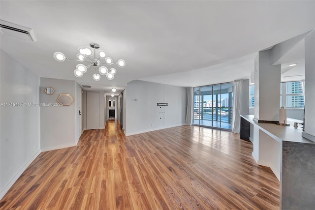 unfurnished living room featuring hardwood / wood-style floors, expansive windows, and an inviting chandelier