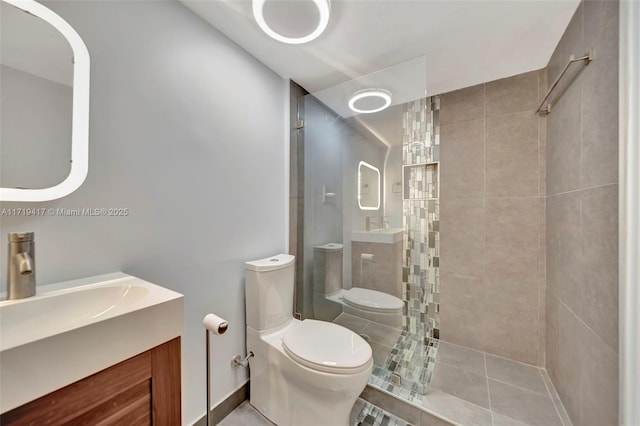 bathroom with tiled shower, tile patterned flooring, vanity, and toilet