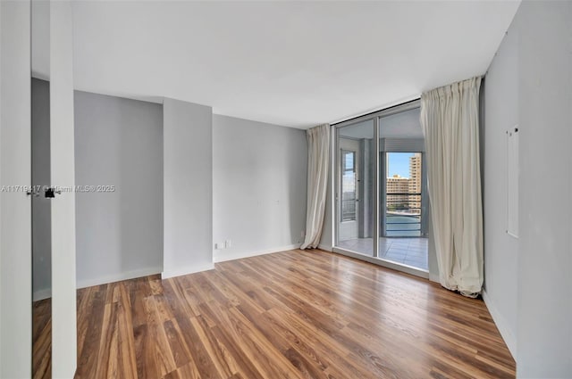 spare room with expansive windows and wood-type flooring