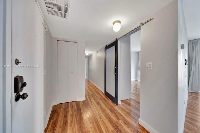 hallway featuring a barn door and light hardwood / wood-style flooring