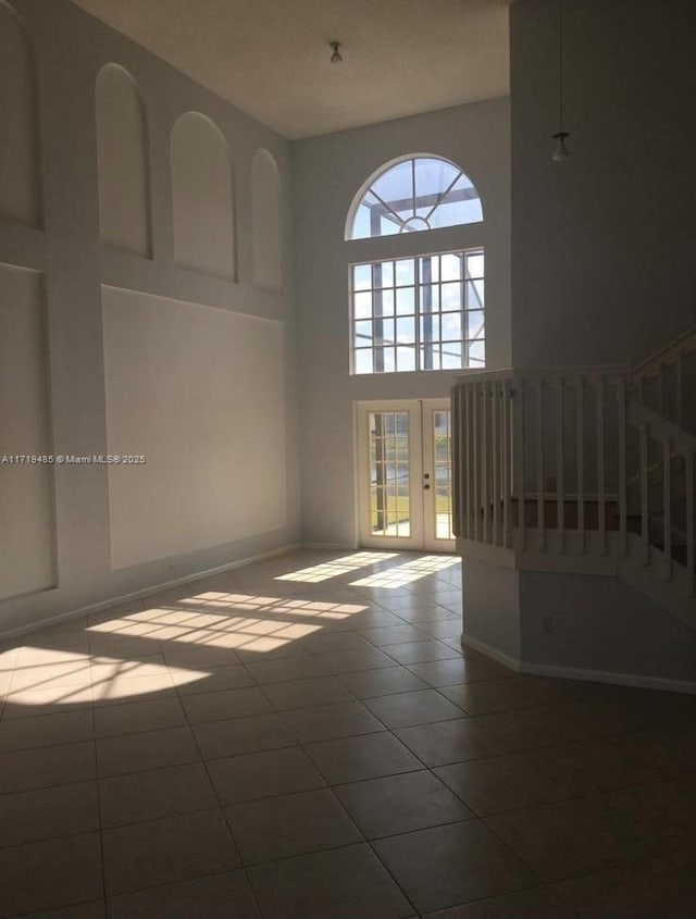 tiled empty room with a towering ceiling and french doors