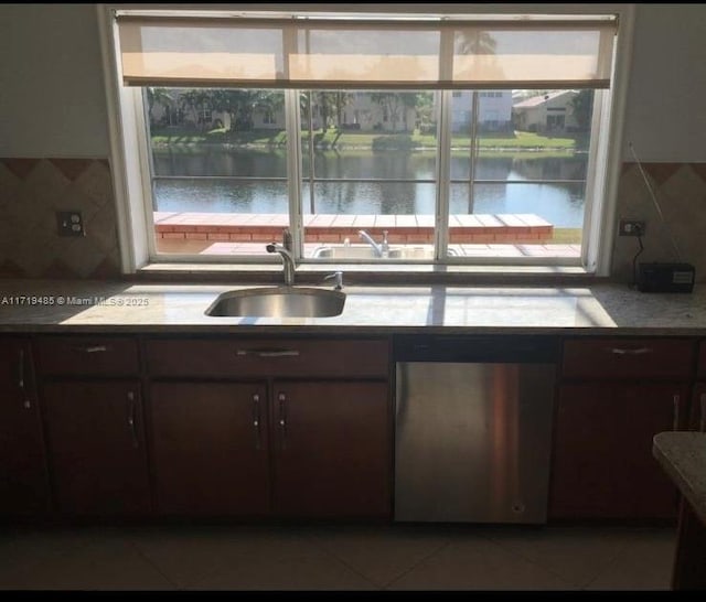 kitchen featuring dark brown cabinets, backsplash, a water view, and sink