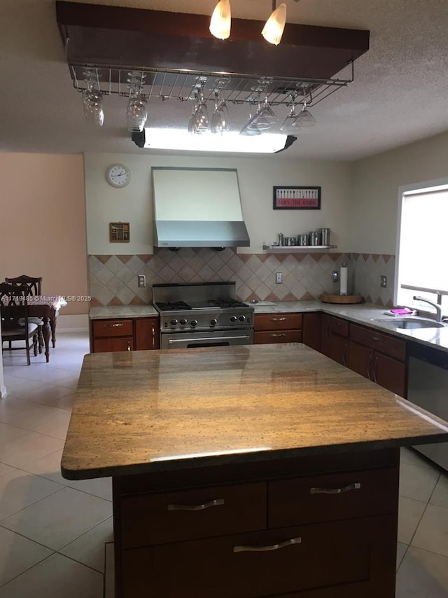 kitchen with tasteful backsplash, extractor fan, sink, high end stainless steel range, and a center island