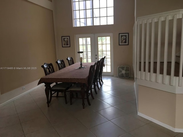 dining area featuring light tile patterned flooring, french doors, and a high ceiling