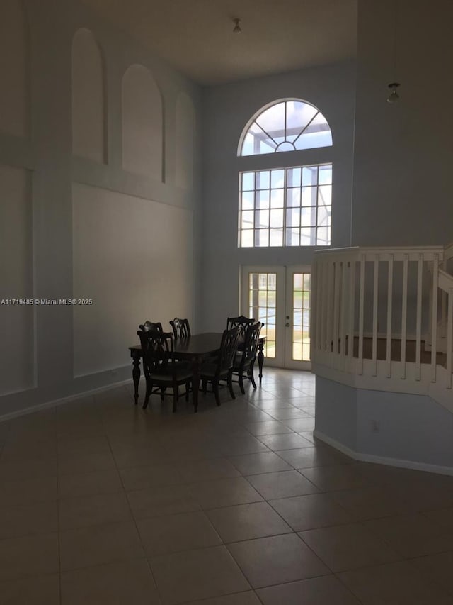 tiled dining room with french doors and a towering ceiling