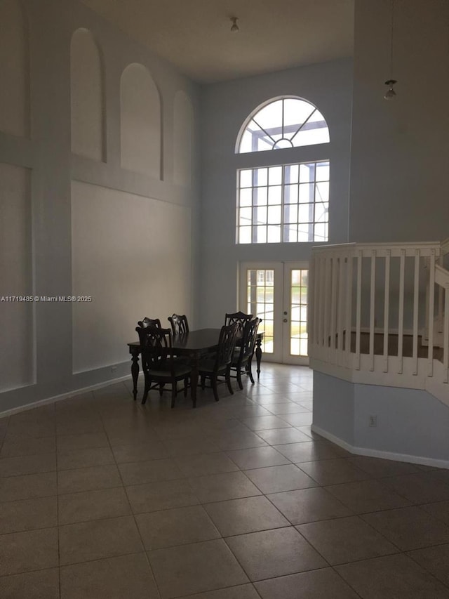 dining room featuring french doors, dark tile patterned flooring, plenty of natural light, and a high ceiling