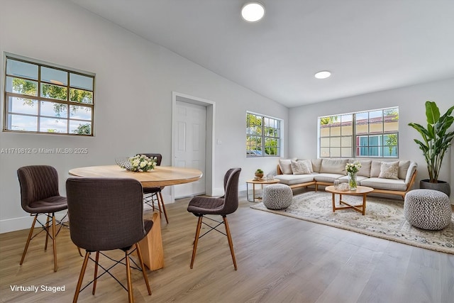 dining area featuring baseboards, lofted ceiling, and light wood-style flooring