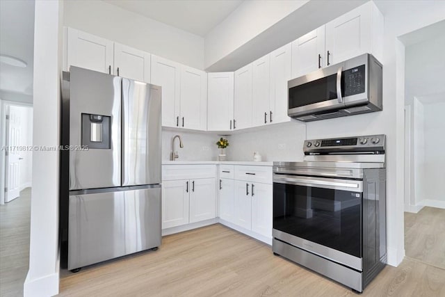 kitchen featuring light wood-type flooring, white cabinets, and stainless steel appliances