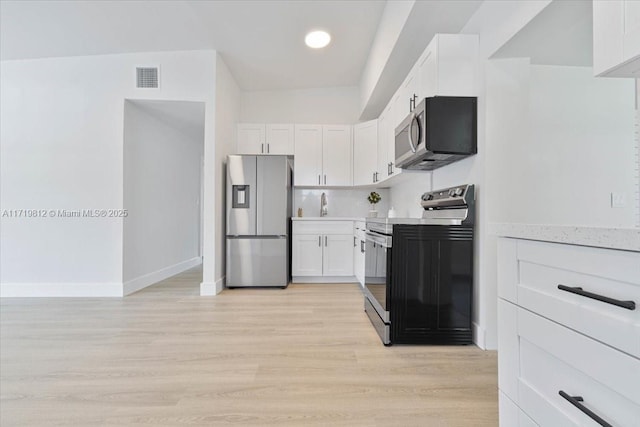 kitchen with light countertops, white cabinetry, appliances with stainless steel finishes, light wood-type flooring, and visible vents