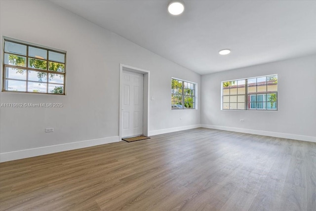 spare room with baseboards and wood finished floors