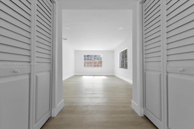 corridor featuring baseboards and light wood-type flooring