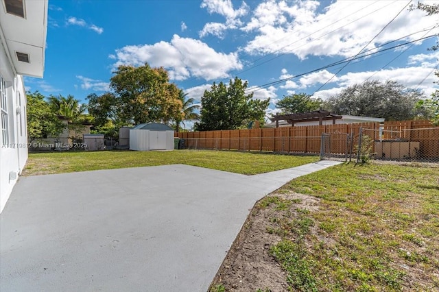 view of yard with a fenced backyard, a shed, an outbuilding, and a patio area