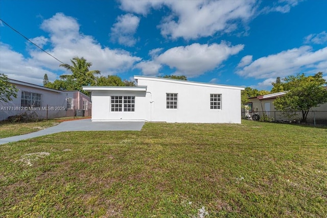 rear view of property with fence, a patio, central AC, stucco siding, and a yard